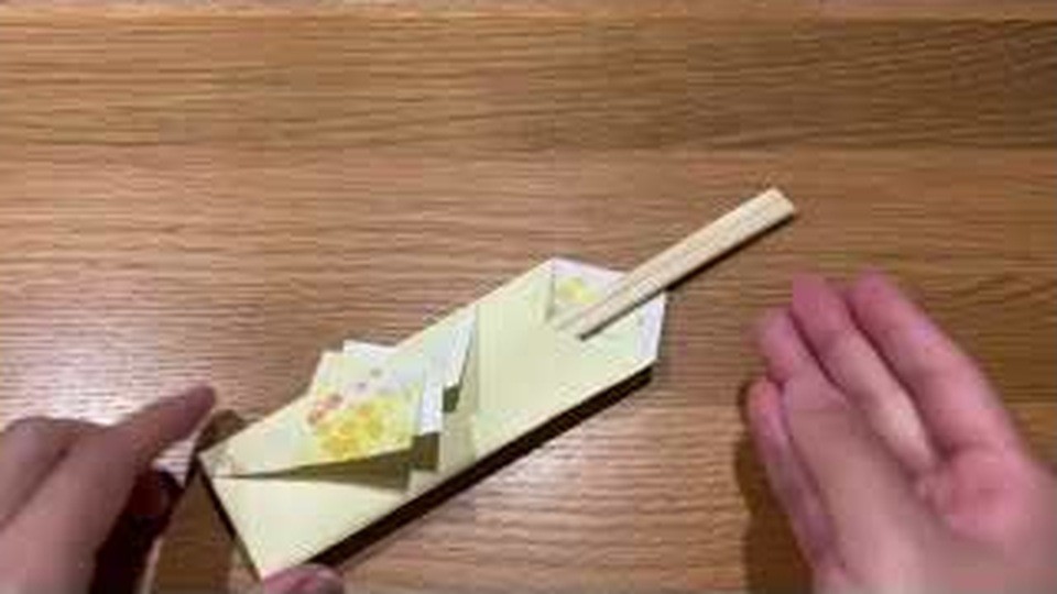 黄色い花柄とうす黄色の紙で折った箸袋に、お箸が1膳差してある様子