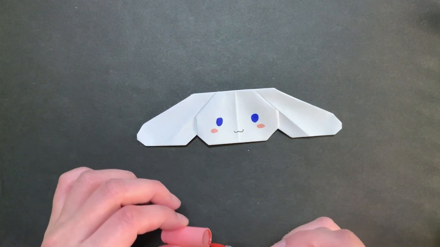 白い折り紙で折り、青い目とピンクのほっぺを描いたお顔だけのシナモロール