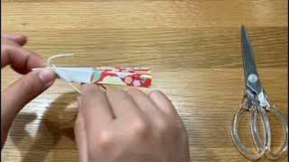 細くたたんだ紙の端に白いひもが出ているのを、手で持っているところ