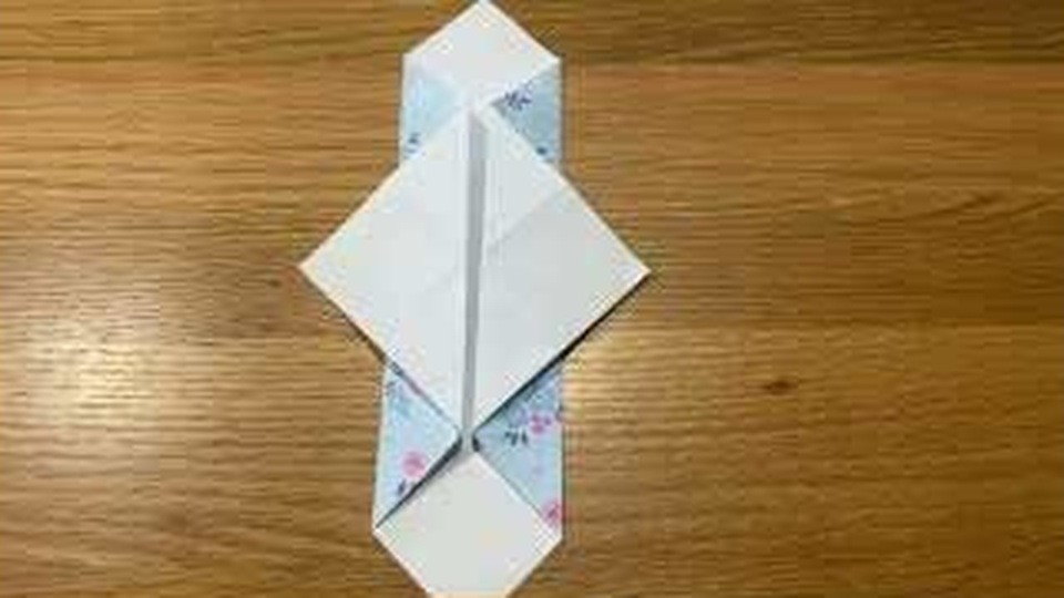 水色の柄の面が見える細長い形の中央に、白い面の菱形が重なって机の上に置かれている