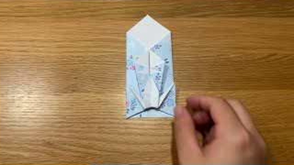 縦長の袋の中央に鶴のような形がのぞき、下側が少し開いた状態で机の上に置かれている